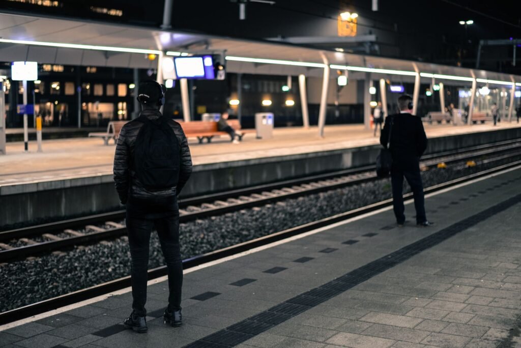 Klein treinstation in Nederland in de avond met warme verlichting en een wachtende reiziger