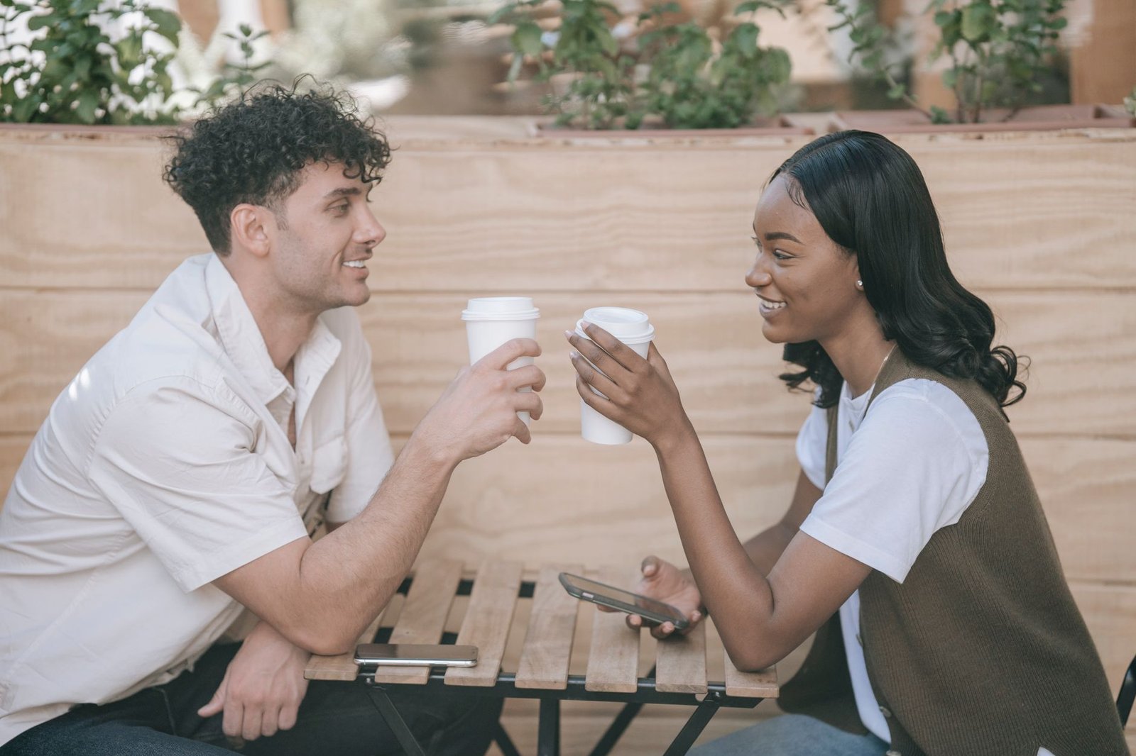 Twee volwassenen delen een moment met koffie buiten, wat verbinding en ontspanning laat zien.
