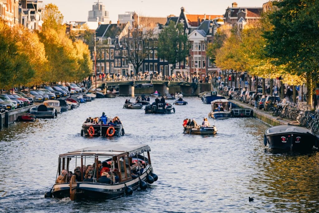 Verken de schilderachtige kanalen van Amsterdam met boten vol toeristen die genieten van de prachtige uitzichten.
