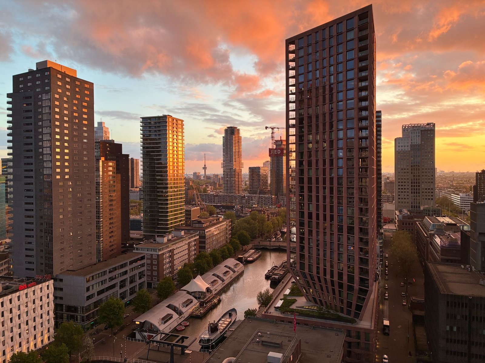 Een adembenemende zonsondergang boven Rotterdam, met de moderne wolkenkrabbers en het bruisende stadsleven prachtig in beeld.