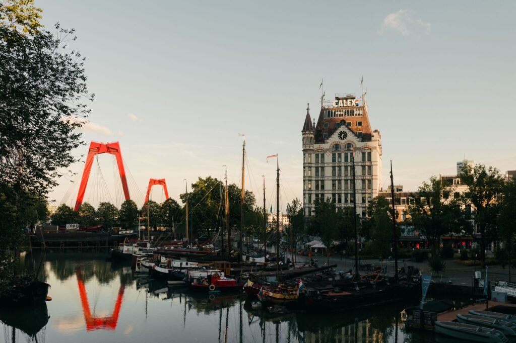 Zonsondergang met uitzicht op de Willemsbrug en de historische haven van Rotterdam, met klassieke architectuur en weerspiegel