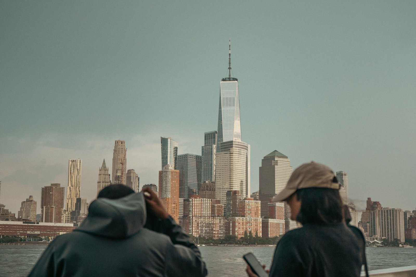 Twee mensen bewonderen de iconische skyline van New York City met het One World Trade Center dat boven alles uittorent.