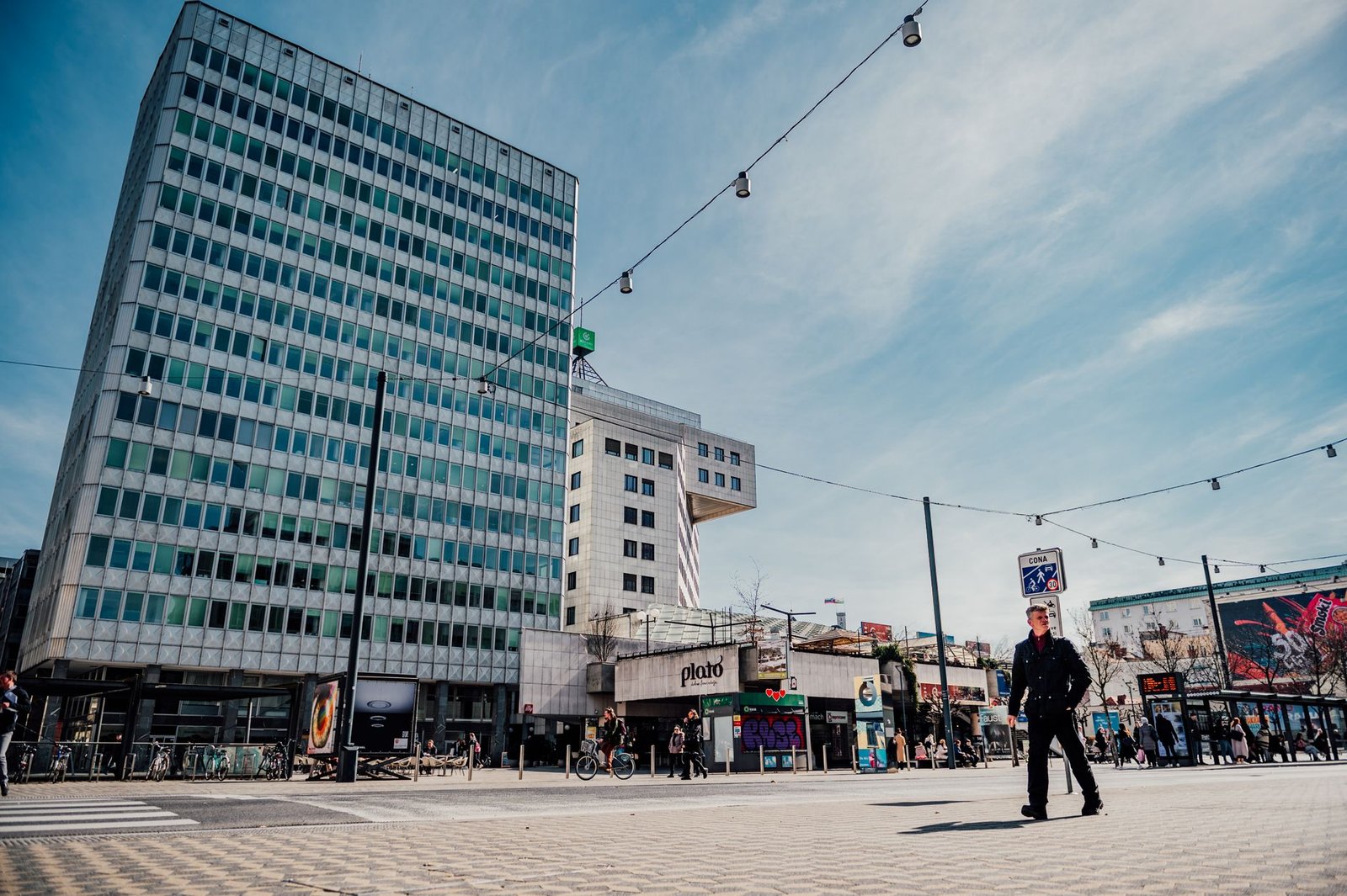 Stedelijk landschap van Ljubljana, met moderne architectuur en voetgangersactiviteit onder een blauwe lucht.