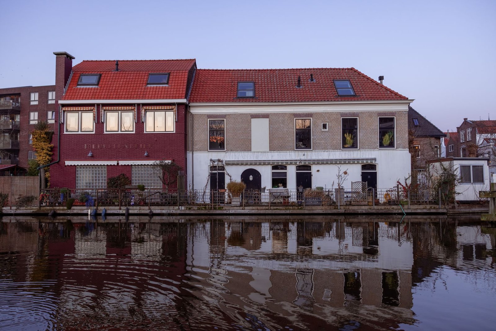 Schilderachtige grachtenpanden in Gouda die bij schemering in het water weerspiegelen.