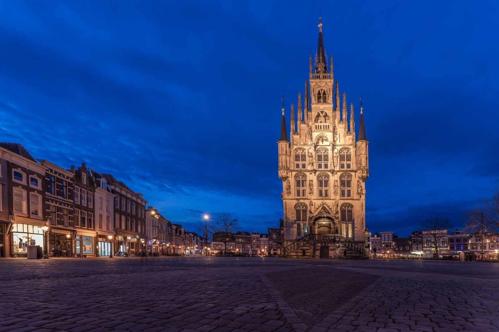 Stadhuis van Gouda illuminated against a deep blue evening sky in Gouda, Netherlands.
