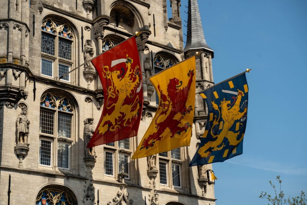 Detail of the historic town hall facade in Gouda, Netherlands with vibrant flags on a sunny day.