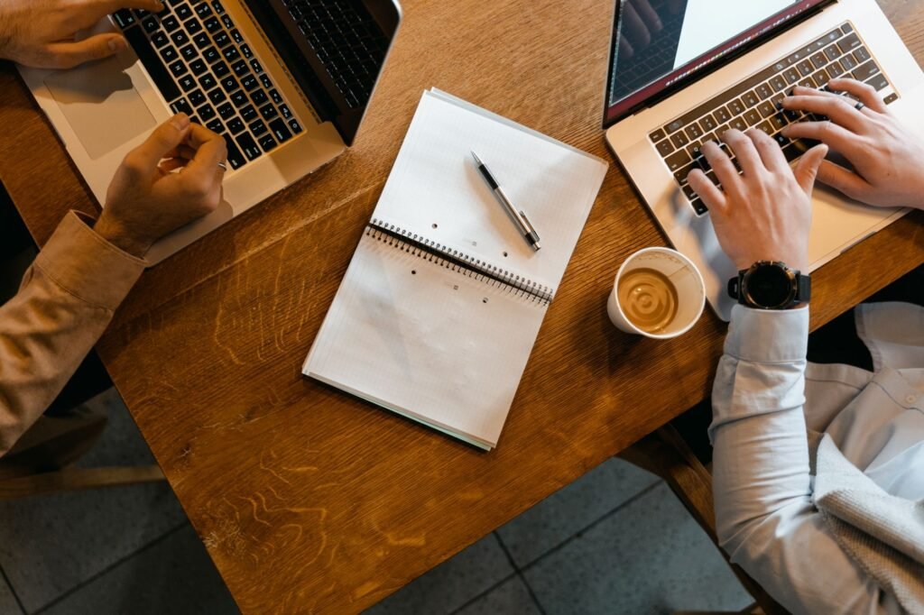 Laptop en notitieblok op een houten tafel, symbool voor het zorgvuldig lezen van profielen