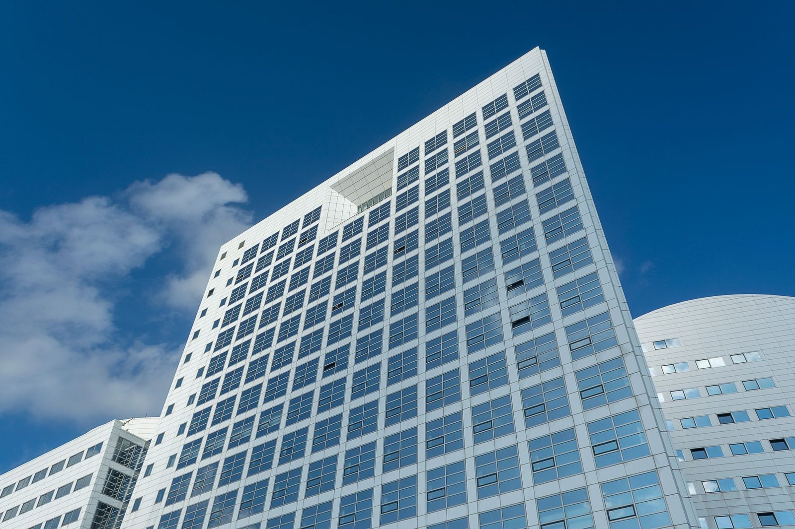 Indrukwekkende laaghoekopname van een moderne wolkenkrabber in Den Haag, Nederland, tegen een heldere blauwe lucht.