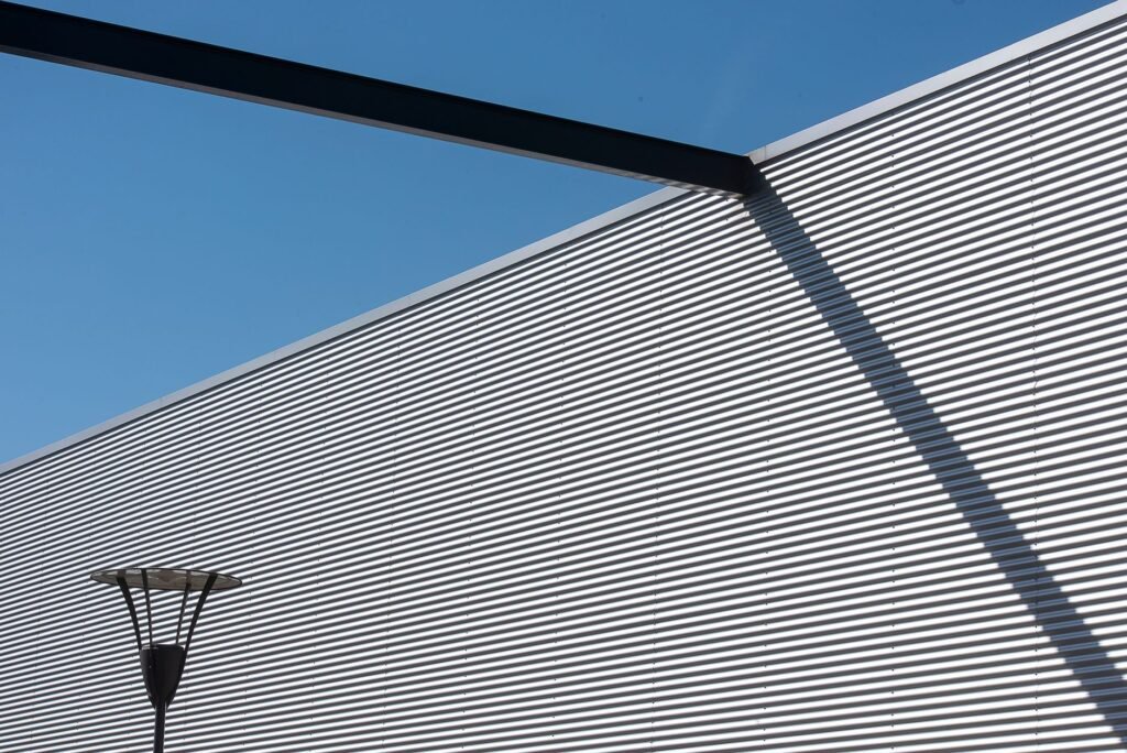 Minimalistisch buitenaanzicht van een modern gebouw met schaduwpatronen op een zonnige dag.