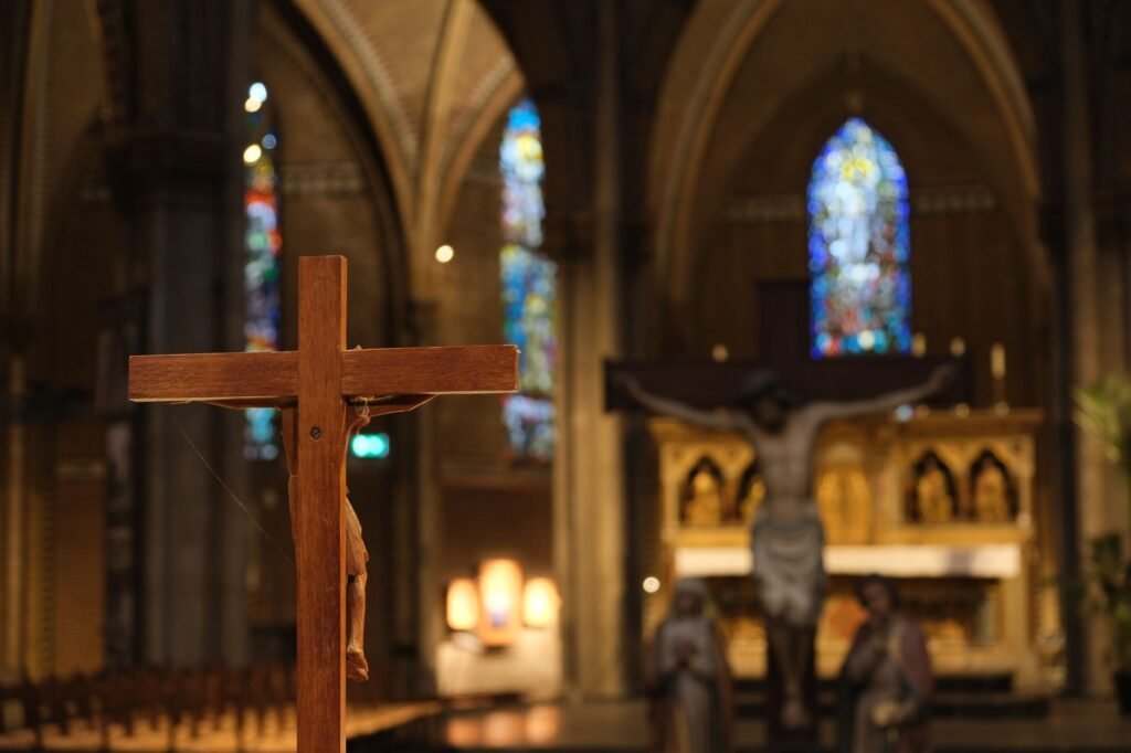 Een scherp zicht van een houten kruis in de Sint-Catharinakerk in Eindhoven met gekleurd glas op de achtergrond.