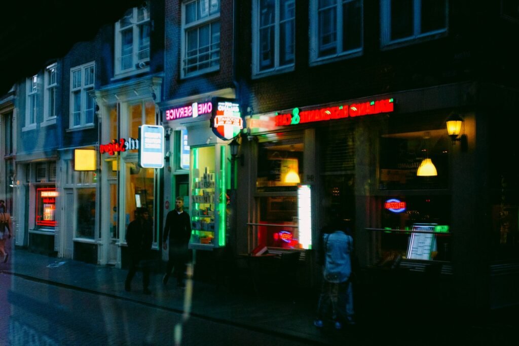 Urbane nacht-scène met neonverlichte winkels en voetgangers op een drukke stadsstraat.