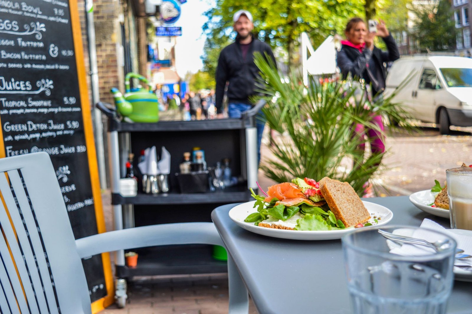 Een levendig buitencafé-scène met een verse sandwich en salade op een zonnige dag.