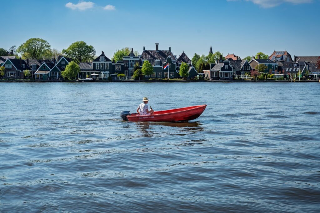 Een persoon in een rood bootje geniet van het prachtige uitzicht op de traditionele Nederlandse architectuur op de Zaanse Sch