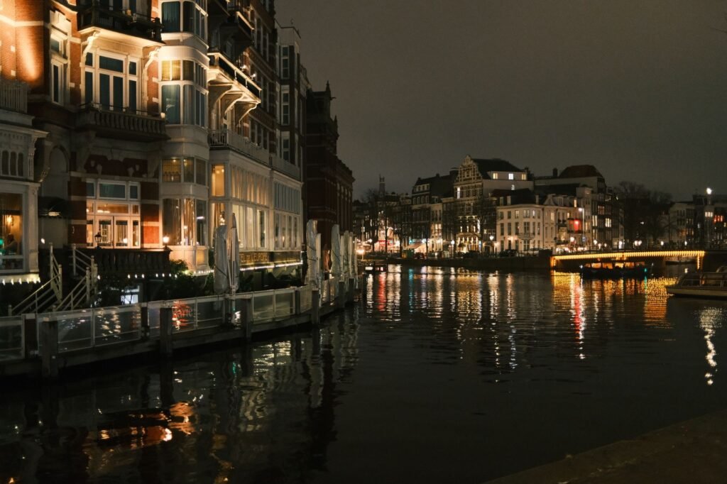 Schilderachtig nachtzicht op de Amsterdamse grachten met verlichte gebouwen die in het water weerspiegelen.