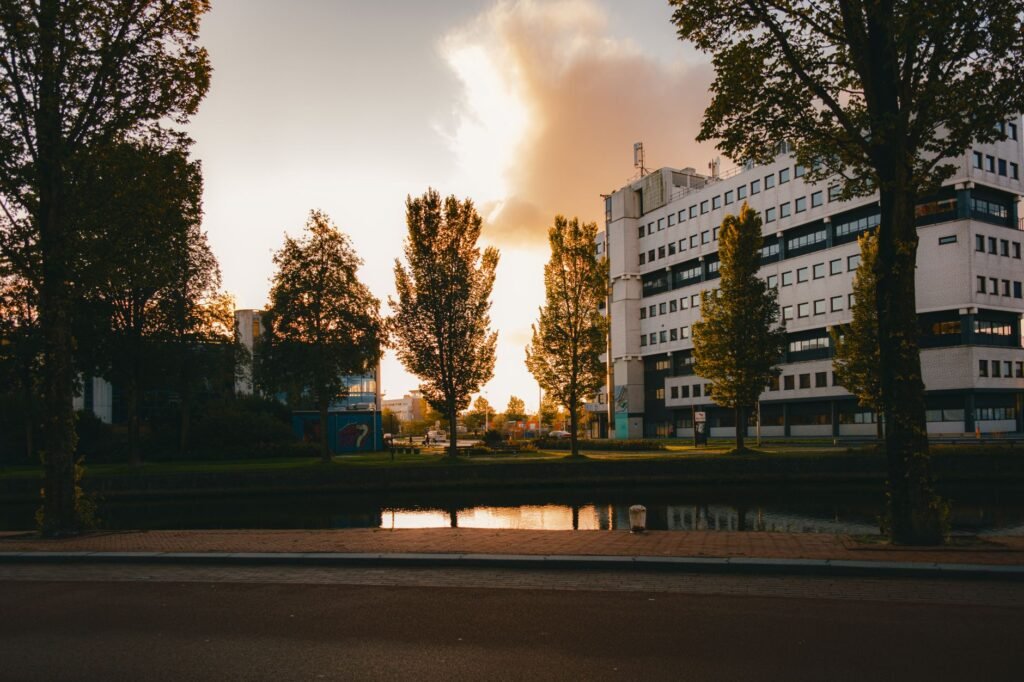 Prachtige zonsondergang boven een kanaal in Leeuwarden, met reflectie van moderne architectuur en bomen.