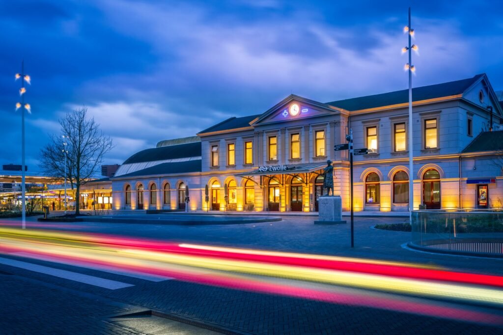 Een adembenemende avondfoto van het Zwolle treinstation, verlicht met levendige lichten.